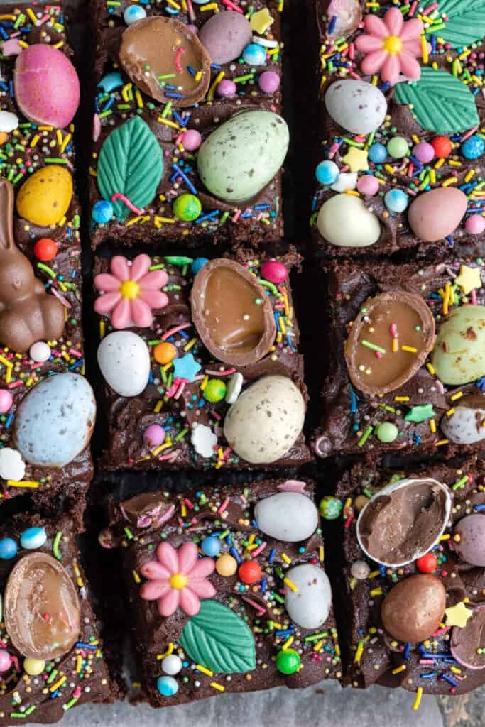 Easter traybake cake decorated with mini eggs and Easter candy, sliced