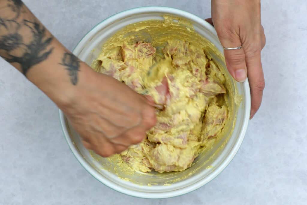 stirring chicken in curry marinade