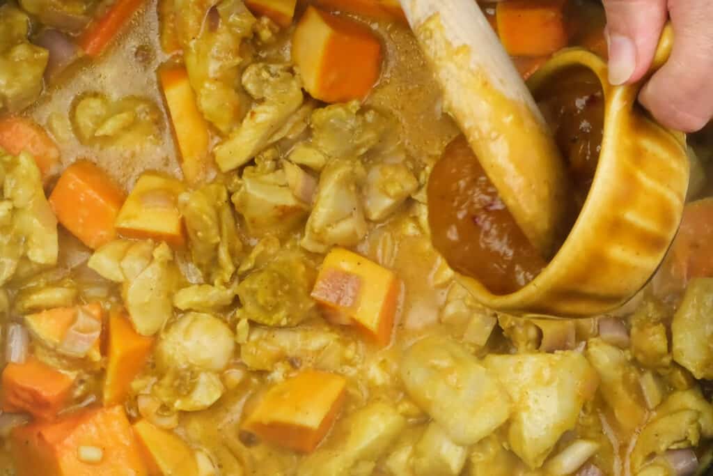 adding mango chutney to Coronation chicken curry in a pan