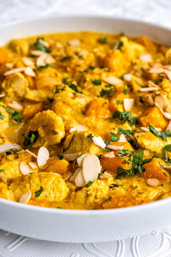 Coronation Chicken curry in a large bowl garnished with coriander and flaked almonds