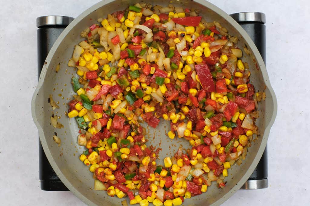 onion, garlic, corn and peppers in a pan