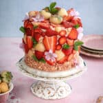 strawberry crunch cake decorated with fresh strawberries on a cake stand