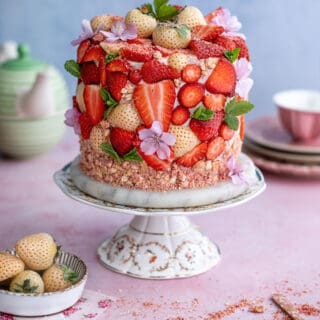 Strawberry crunch cake on a cake stand decorated with sliced strawberries