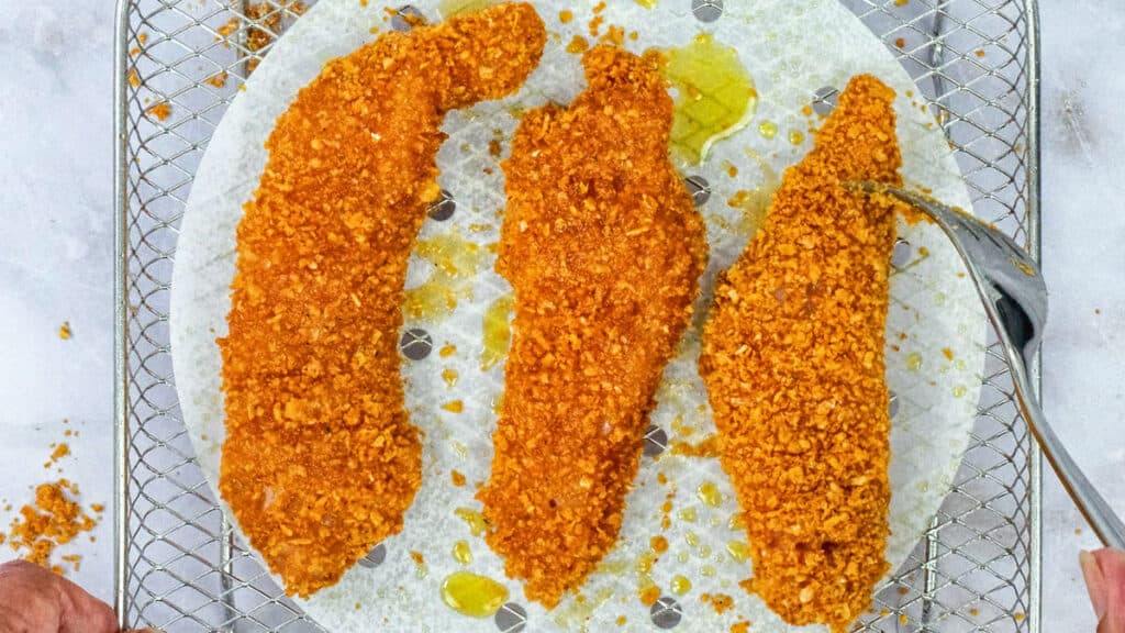 Chicken tenders with crunchy cornflake coating in an air fryer rack
