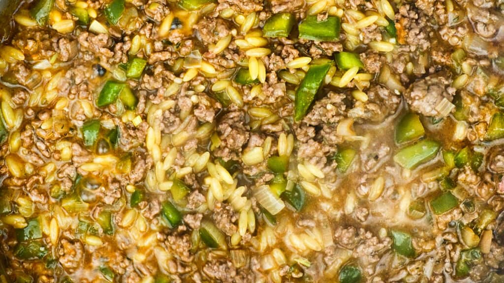close up on a pan of Cajun dirty orzo cooking in a pan