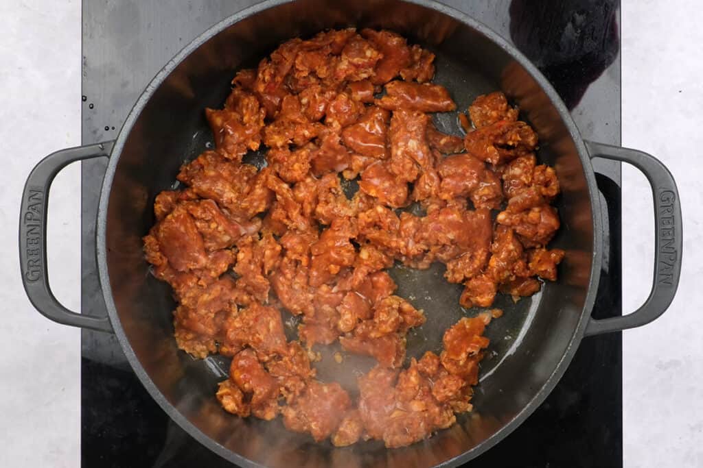 crumbled spicy sausage cooking in a Dutch oven