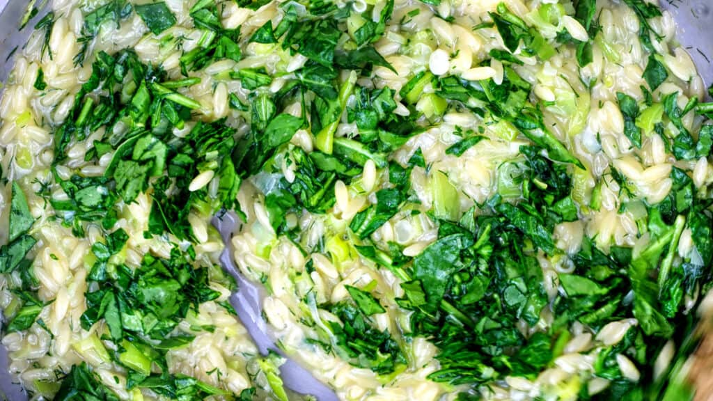 stirring spinach orzo, close up
