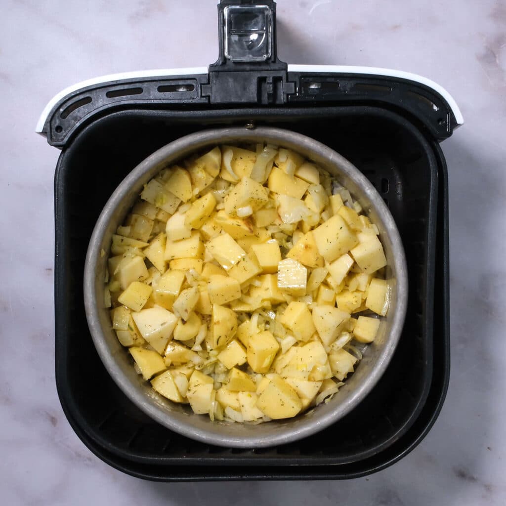Onion and cubed potatoes cooking in an air fryer