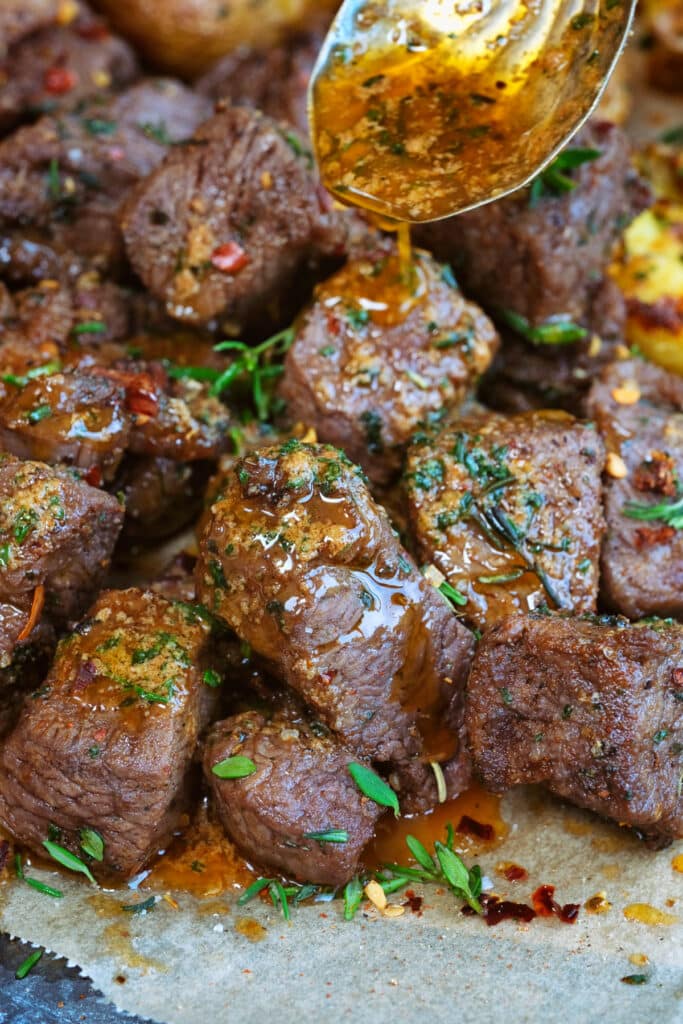 close up on air fryer steak bites drizzled with garlic butter
