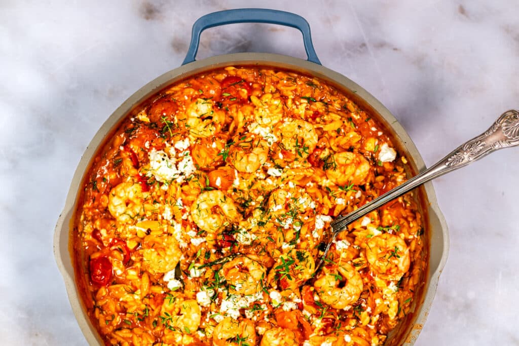 Skillet with shrimp orzo cooked with tomatoes and topped with feta cheese