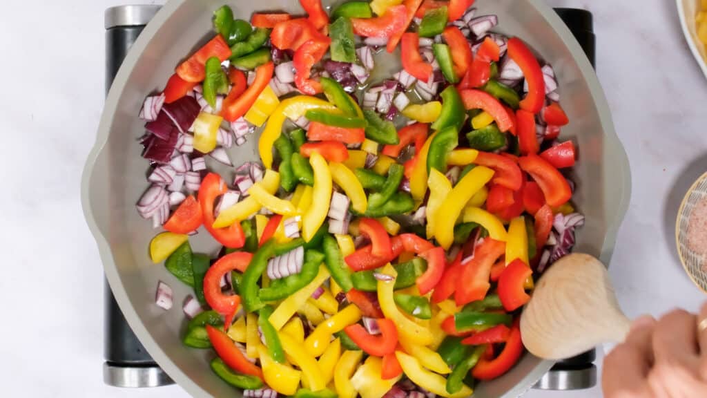 cooking onion and bell peppers in a pan