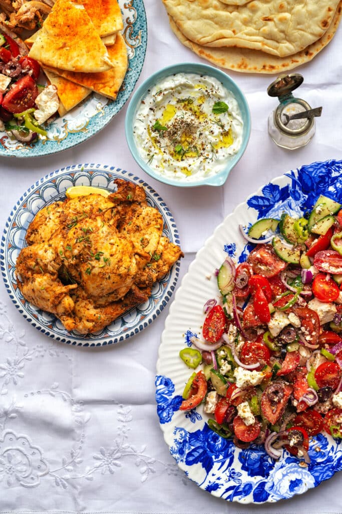 Table set with Greek salad, tzatziki, chicken and pita bread