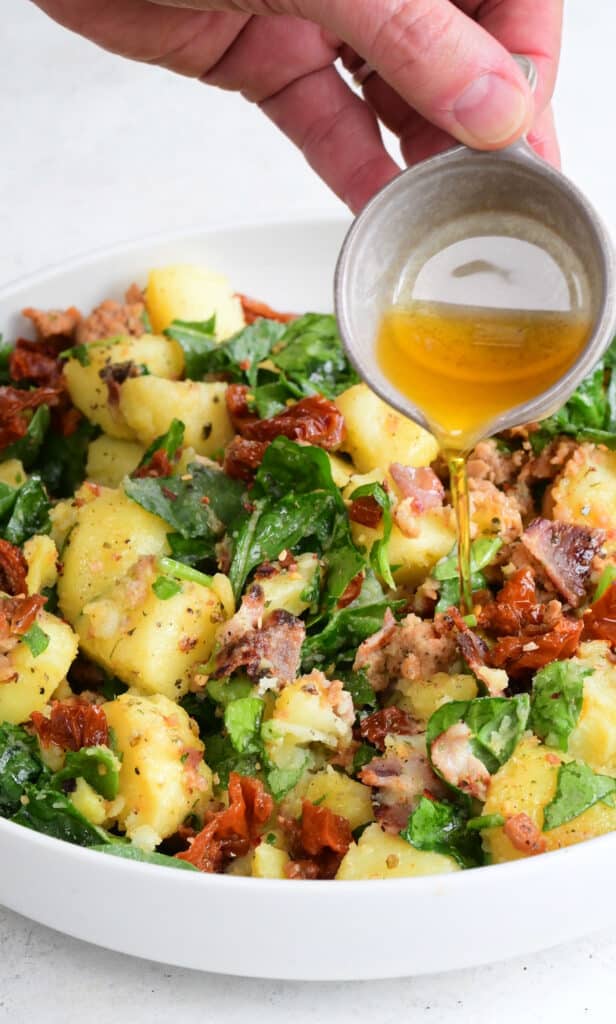 Drizzling warm potato salad with olive oil
