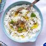 bowl of Greek Tzatziki garnished with fresh herbs and olive oil