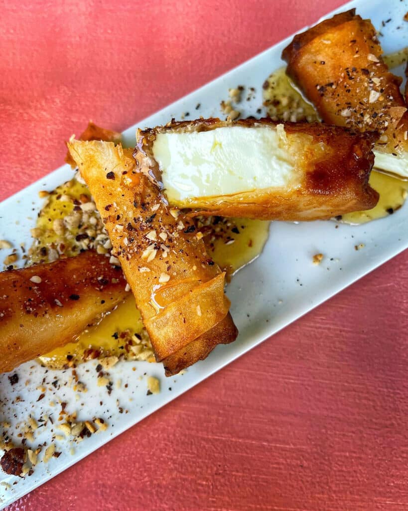 Fried feta rolls on a plate served with honey and nuts