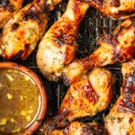 Close up on Air Fryer chicken drumsticks with a bowl of marinade on the side