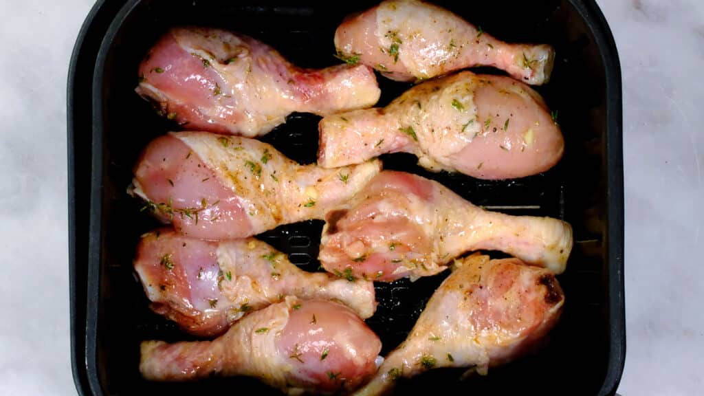 raw marinated chicken legs in the basket of an air fryer