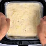 putting a pan of lasagna in an air fryer basket