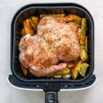 Whole raw chicken breast side down in an air fryer basket