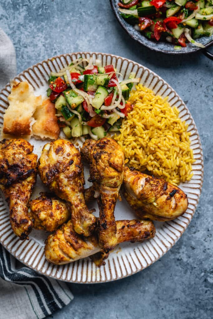 Air fried Tandoori chicken drumsticks served with pilau rice and cucumber tomato salad