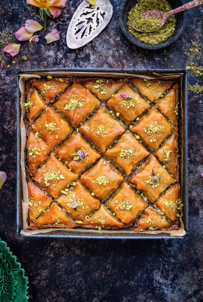 Greek baklava cut into a diamond pattern topped with chopped pistachions, top view