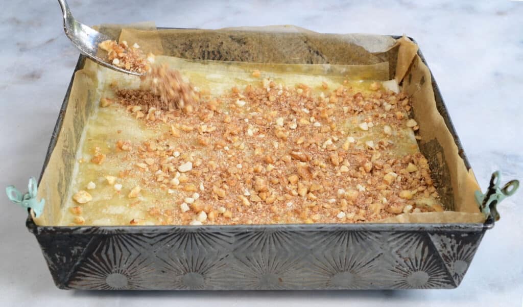 sprinkling chopped walnuts over phyllo pastry