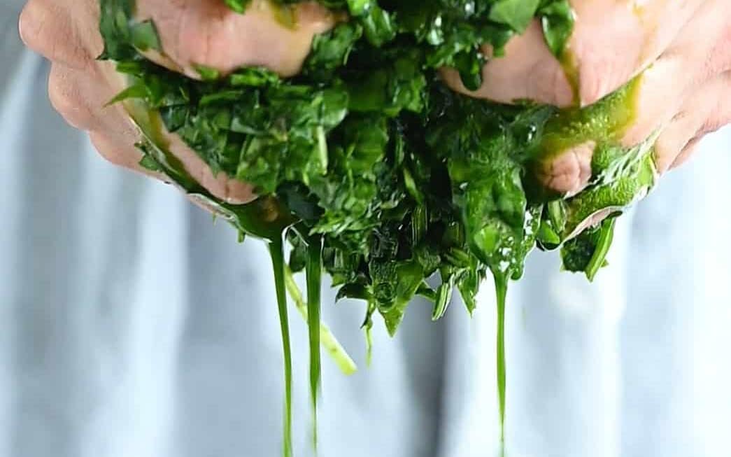 squeezing chopped spinach over a bowl to get rid of liquid