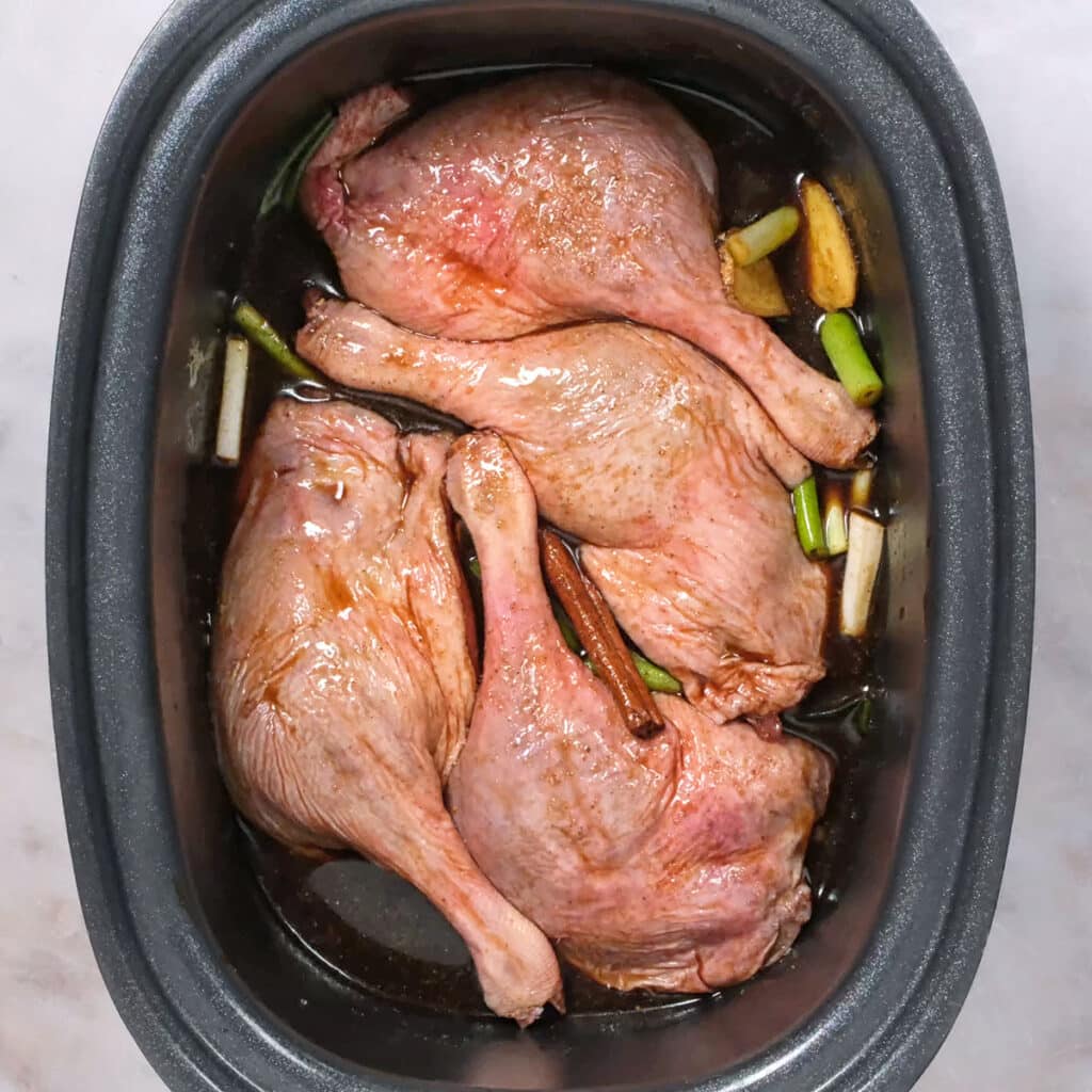 Duck legs marinating in a slow cooker insert