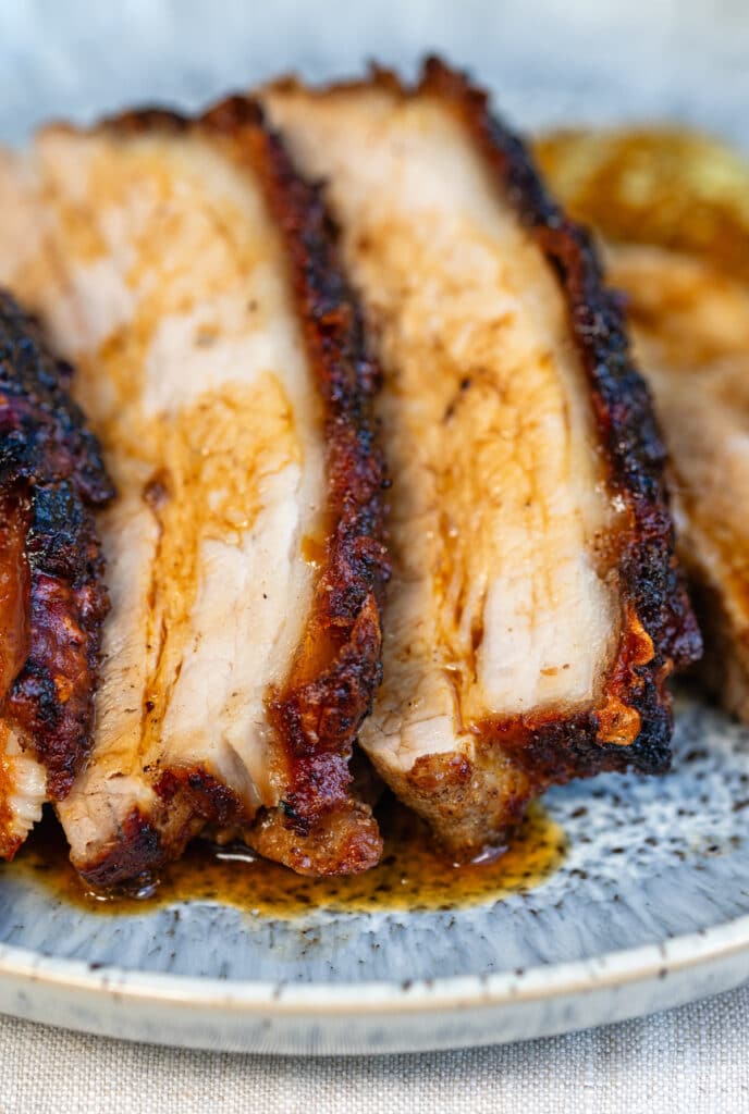 Thick slices of crispy roasted pork belly on a plate