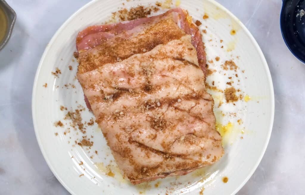 pork belly rubbed with salt and seasonings on a white plate