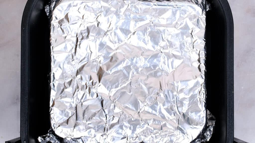 dish covered with foil in the basket of an air fryer