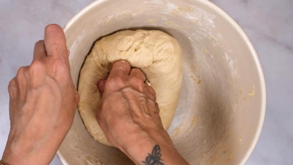 kneading bread dough in a mixing bowl