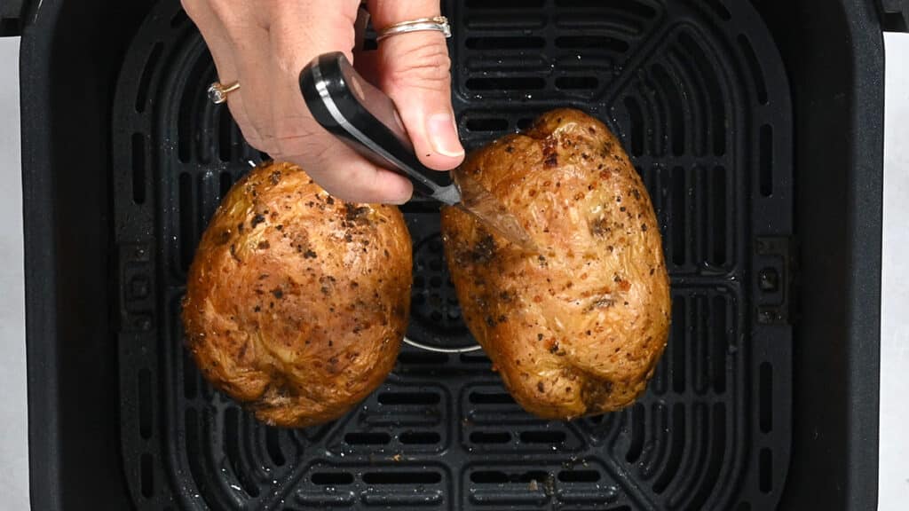 checking whether a baked potato is cooked through by piercing with a knife