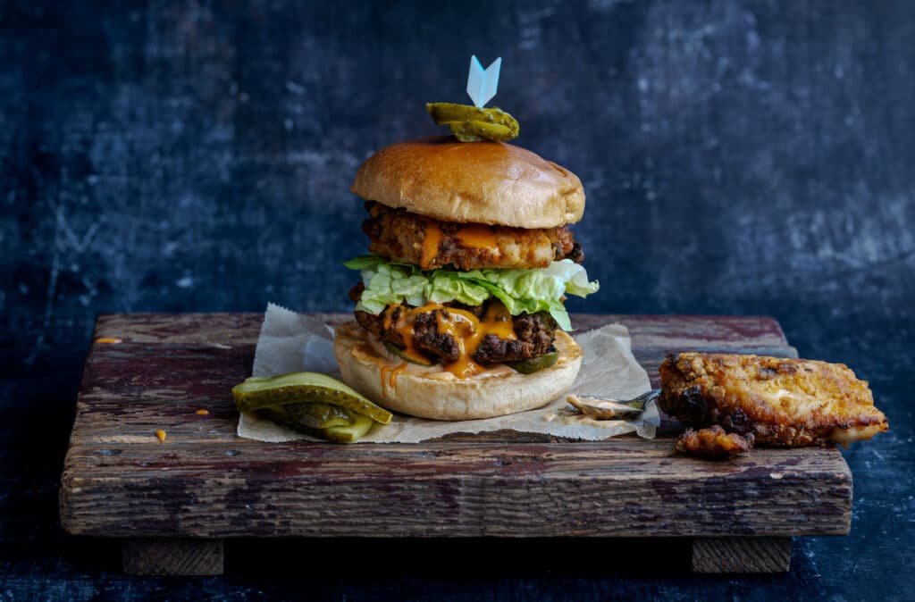 Popeye's style fried chicken sandwich on a wooden board with pickles on the side