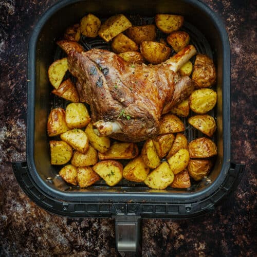 Roast half leg of lamb and potatoes in the basket of an air fryer