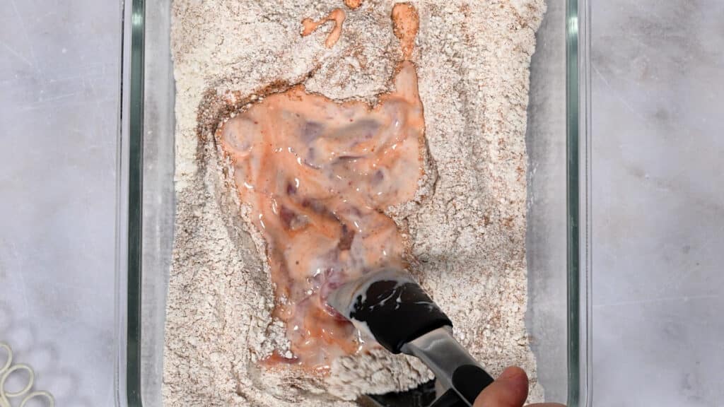 dredging marinated chicken in flour coating