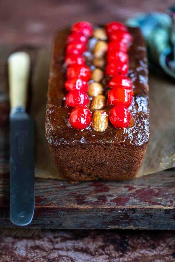 Mincemeat cake topped with cherries and almonds on a wooden board