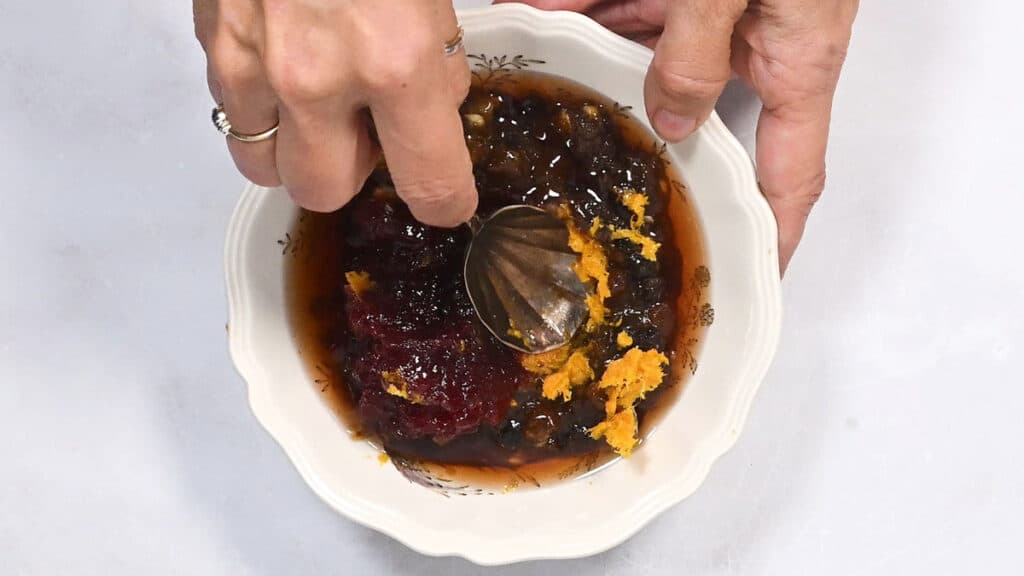 mixing mincemeat with orange zest, brandy and cranberry sauce in a bowl