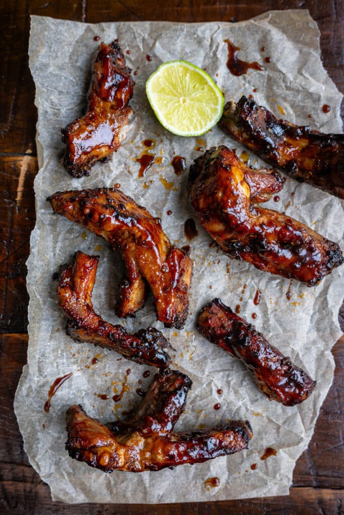 Air fryer pork ribs on parchment paper with half a lime and BBQ sauce