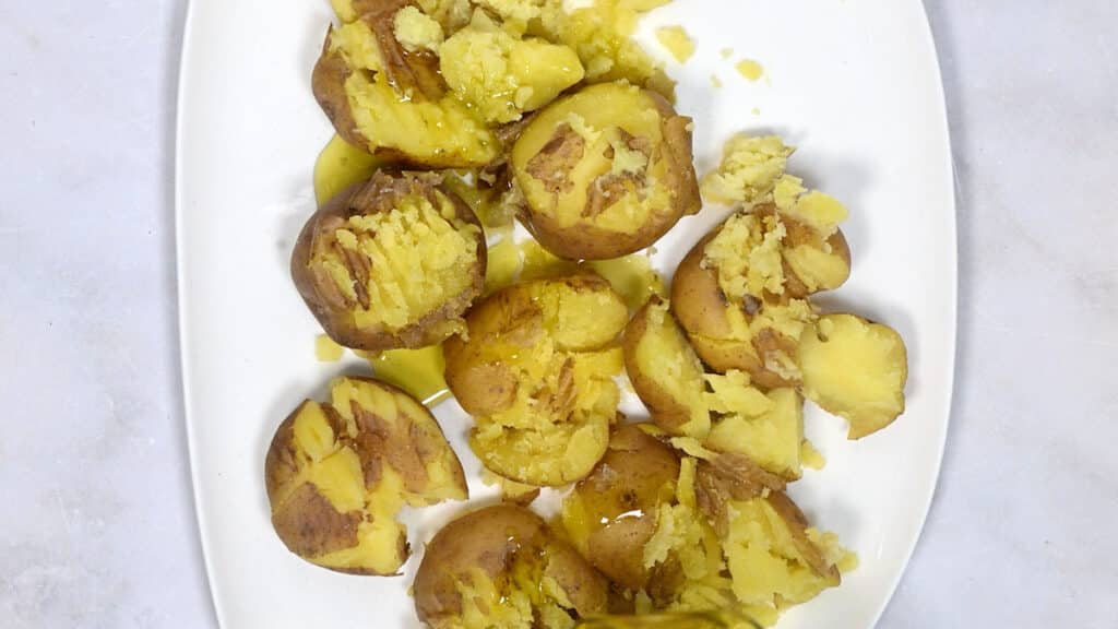 crushed potatoes drizzled with olive oil on a plate