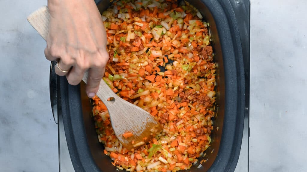 stirring ingredients in a slow cooker to make ragu sauce
