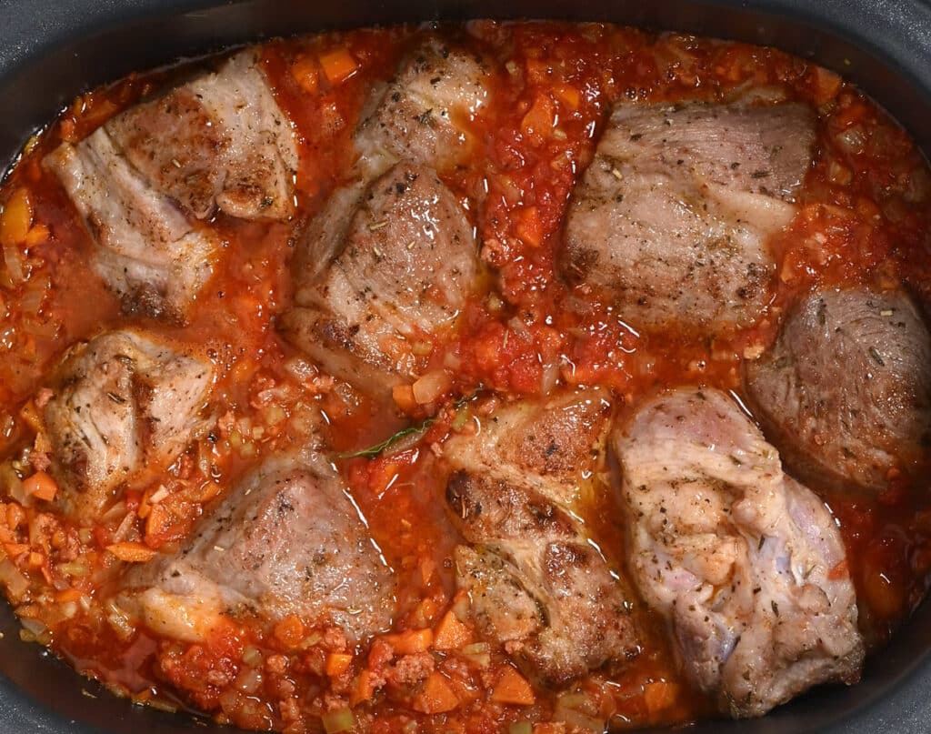 pork pieces simmering in tomato sauce in a crock pot
