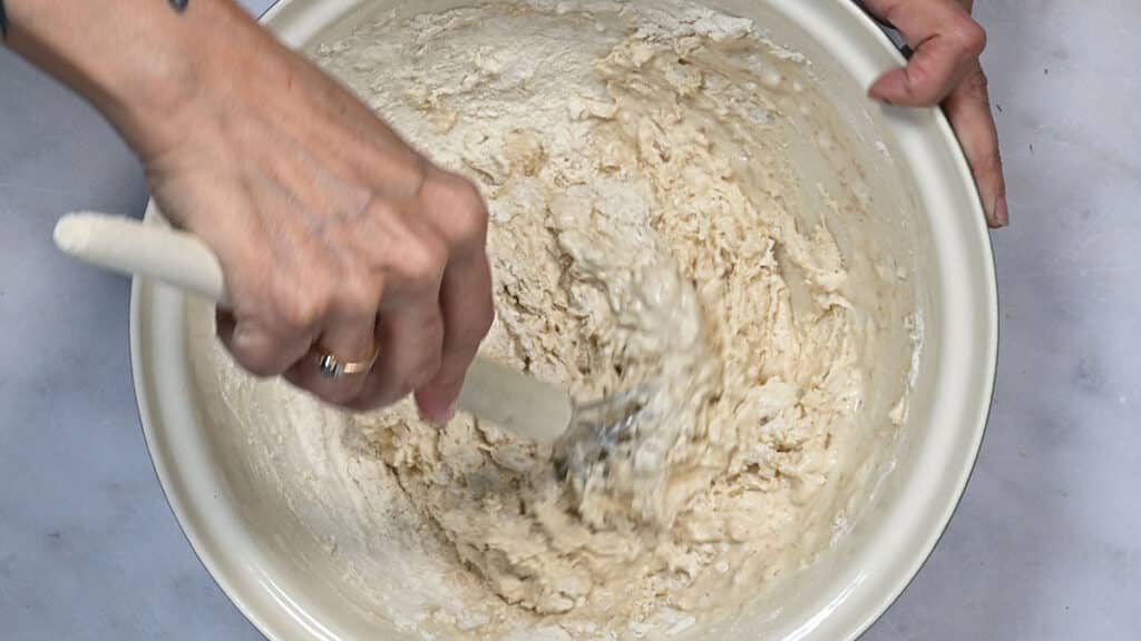 mixing sourdough discard, water and flour in a bowl to make focaccia