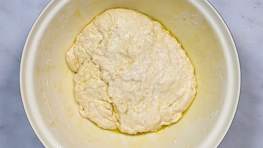 sourdough discard focaccia dough drizzled with olive oil in a bowl
