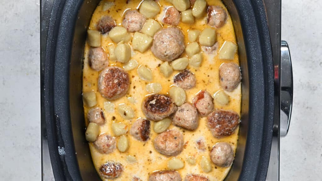 slow cooker meatballs and gnocchi cooking in a creamy broth
