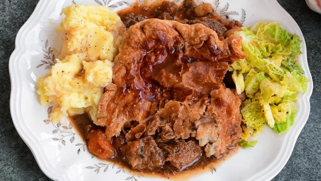 serving of Irish meat pie on a plate with mashed potatoes and cabbage