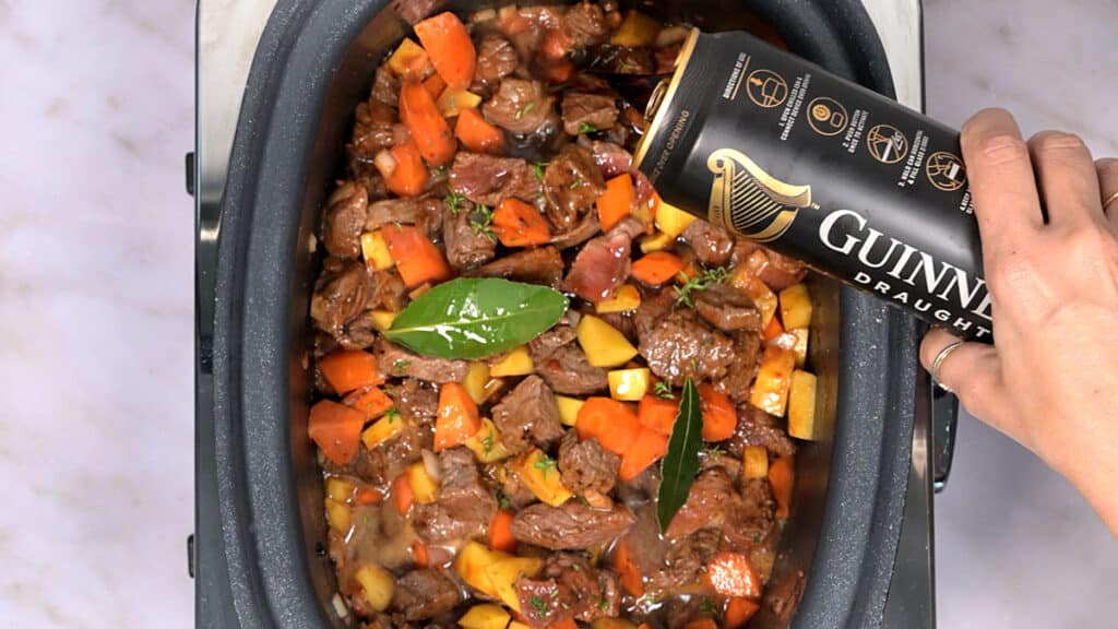adding Guinness into a beef stew cooking in a crock pot