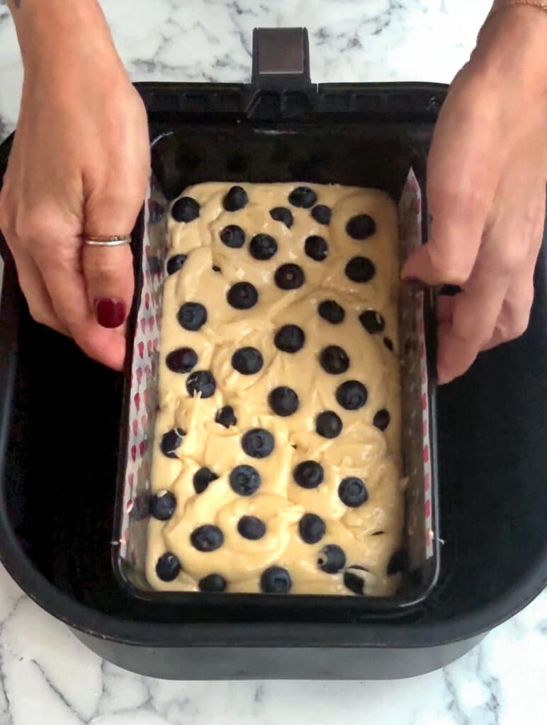 putting a lemon and blueberry loaf into an air fryer basket