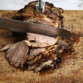 Slicing air fryer lamb shoulder on a cutting board