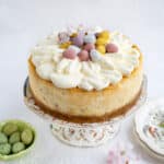 Mini egg cheesecake decorated with whipped cream and Cadbury's mini eggs on a cake stand